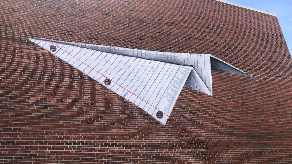 paper airplane mural of a paper airplane painted on a brick wall