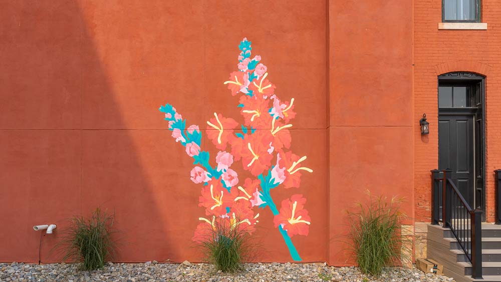 The Studio Wahl mural of orange flowers and green stems on an orange wall