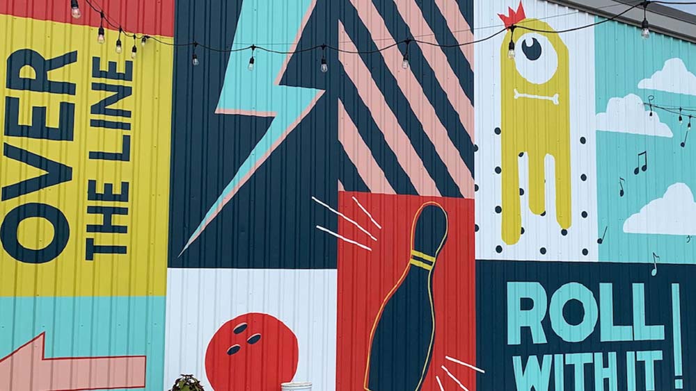 A closeup of the Wayward Social exterior mural with a bowling pin, stripes, lightening bolt and alien pictured
