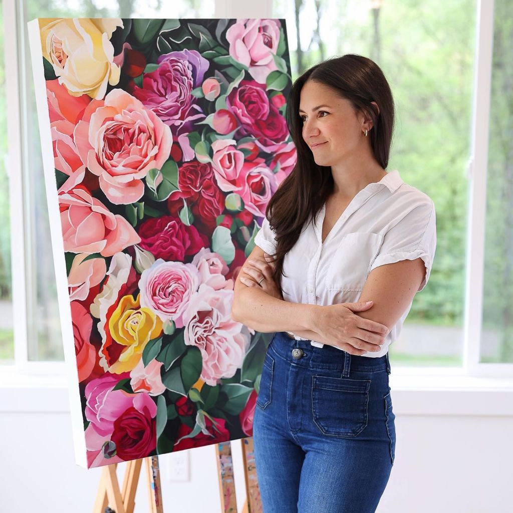 Jenna Brownlee standing in front of a brightly colored painting of flowers