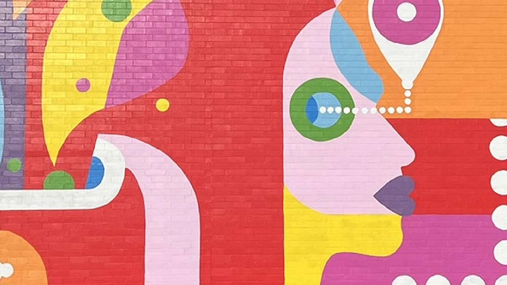A closeup of the Orpheum mural with a stylized face, white circles, and large areas of red, pink, orange and yellwo