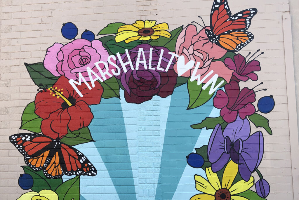 A closeup of purple and pink and yellow flowers and a monarch butterfly in Marshalltown's Selfie Mural