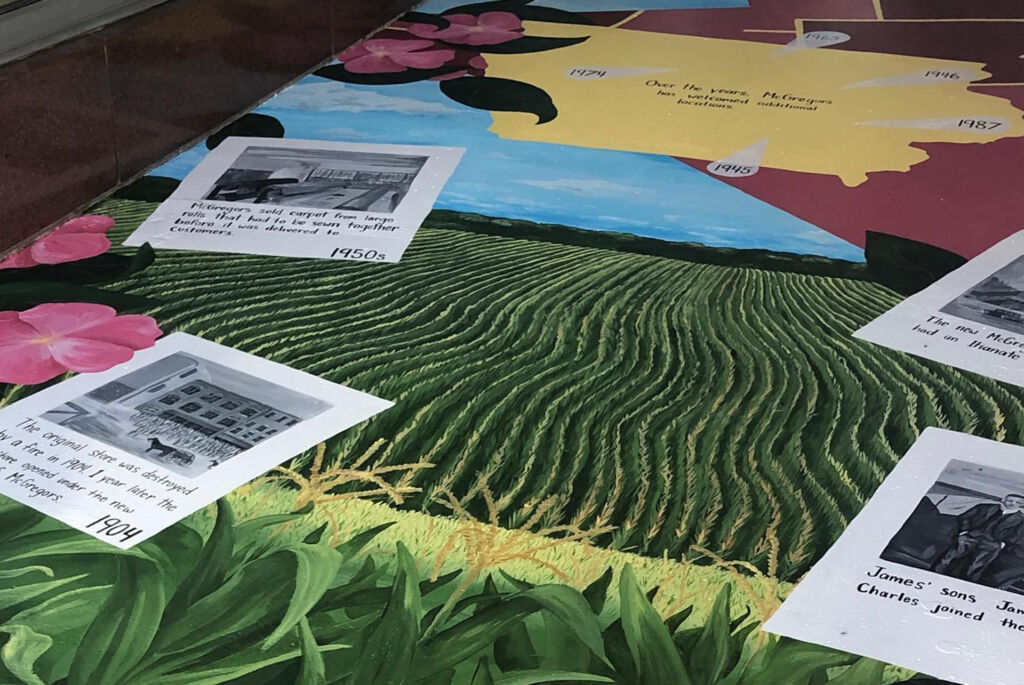 A closeup of the McGregor's mural with farm fields and dated painted photos of historical moments