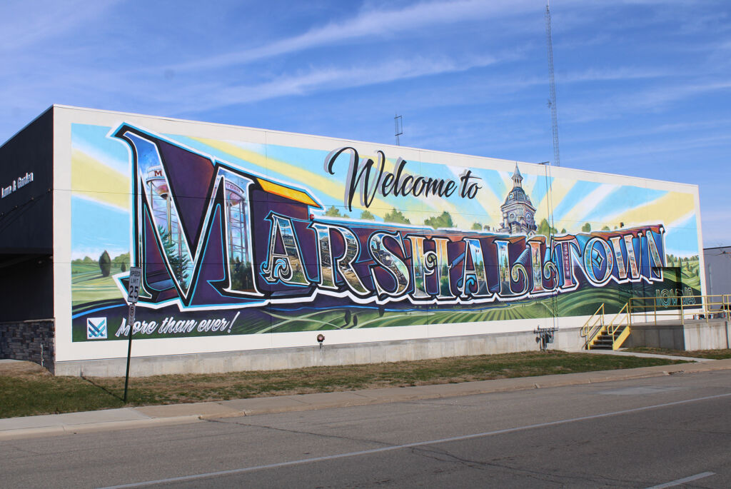 A full exterior wall mural that reads 'Welcome to' in script above large letters that read 'MARSHALLTOWN' with images of the city inside each letter