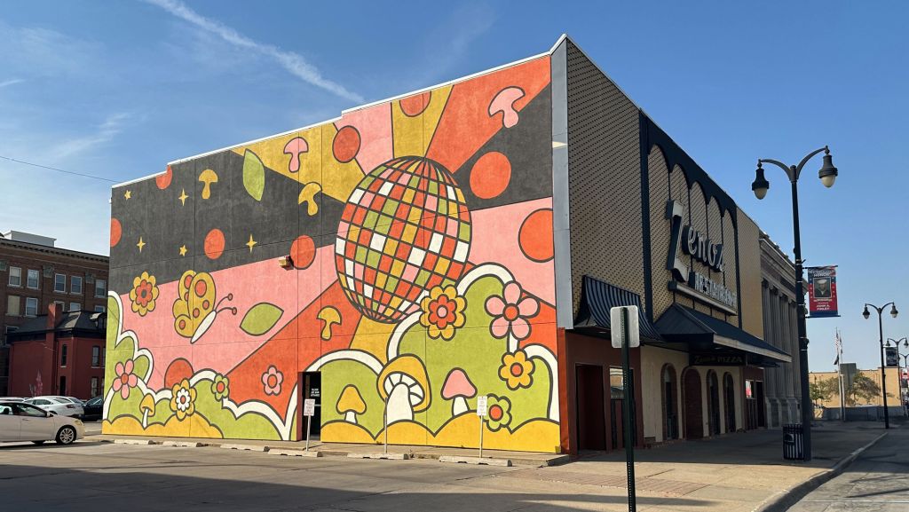 A corner view of the Zeno's Pizza Mural depicting a colorful and whimsical scene with a disco ball, pizza toppings and flowers