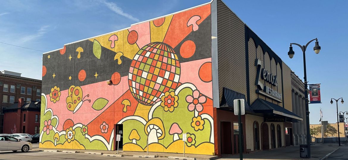 A corner view of the Zeno's Pizza Mural depicting a colorful and whimsical scene with a disco ball, pizza toppings and flowers